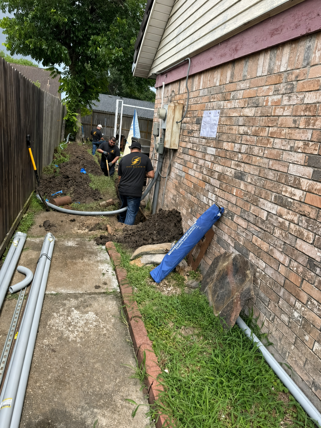 Jeff Electric crew installing residential electrical conduit beside a home