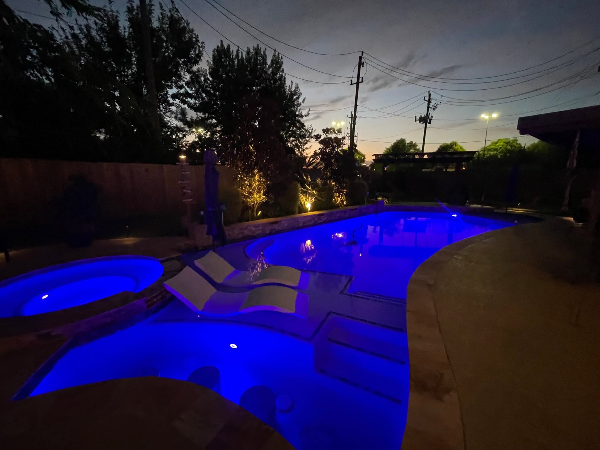 Residential swimming pool illuminated with blue underwater lighting at night